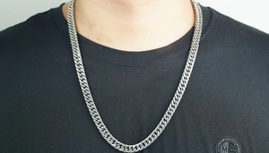 Close-up of thick silver Cuban link necklace worn by a man on a black T-shirt