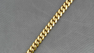 Vue macro d'un collier à maille gourmette dorée polie avec textures métalliques