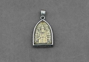 Dettaglio ravvicinato di un ciondolo religioso bicolore con divinità intricata