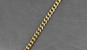 Détail d'un collier à maille gourmette dorée montrant la texture du métal poli brillant