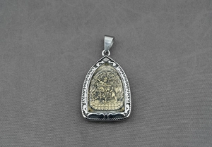 Vue détaillée du pendentif religieux en argent avec relief doré sur tissu gris