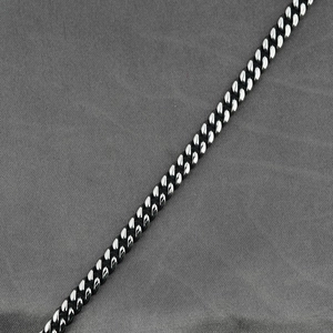 Collana a catena cubana in acciaio inossidabile lucido argento su sfondo in tessuto grigio