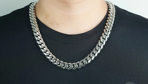 Primer plano de una cadena cubana pesada de acero inoxidable plateada en un modelo hombre