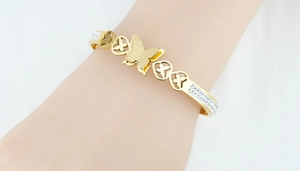 Détail du bracelet papillon doré avec strass et finition mate porté par une femme