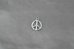 Gros plan détaillé du pendentif symbole de paix en acier inoxydable poli sur fond gris