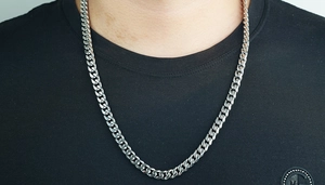 Primer plano de una cadena cubana de acero inoxidable plateado en una camiseta negra