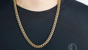 Gros plan d'une chaîne cubaine plaquée or portée sur un t-shirt noir pour homme