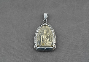 Dettaglio macro del ciondolo Buddha in acciaio inossidabile e ottone con rilievo