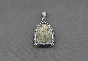 Détail macro d'un pendentif bouddhiste avec relief doré et gravures argentées