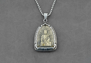 Dettaglio del ciondolo Buddha dorato con rilievo di loto e catena a maglia argento