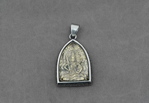 Dettaglio del ciondolo amuleto buddista con intaglio bicolore e finitura in acciaio