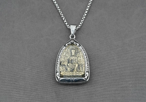 Détail d'un pendentif religieux avec relief bicolore d'une divinité chevauchant une bête