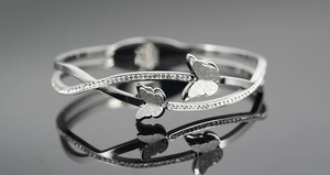 Detail van zilveren vlinderarmring met gezandstraalde vleugels en fonkelende kristallen