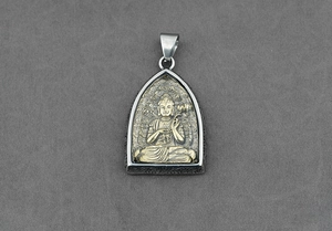 Dettaglio di un ciondolo Buddha tailandese in metallo bicolore con intagli laterali
