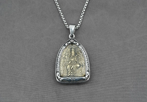 Détail d'un pendentif religieux en forme de bouclier avec relief doré et chaîne à mailles carrées