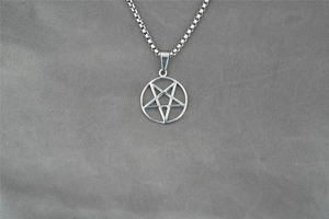 Dettaglio del ciondolo a pentagramma argento su catena box su tessuto grigio