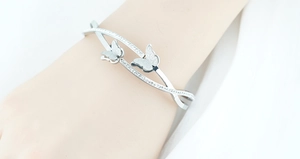 Detailopname van een zilveren vlinderarmring met matte vleugels en micro-pave gezette stenen