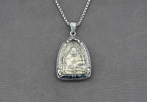 Détail du pendentif bouddha Maitreya doré sur une chaîne en maille miroir argentée