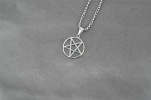 Dettaglio ravvicinato di un ciondolo a pentagramma argento con catena a maglia quadra
