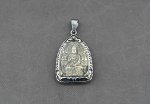 Dettaglio di un ciondolo buddista con Buddha dorato e cornice in argento finemente incisa