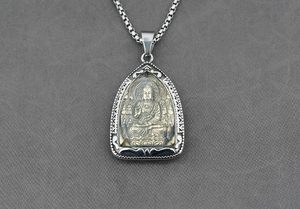 Dettaglio del ciondolo buddista bicolore con intaglio a rilievo e catena in acciaio