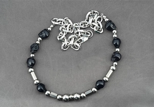 Détail du collier punk avec perles de crâne noires et maillons en acier argenté robuste