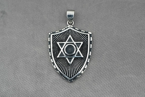 Close-up of vintage shield pendant with engraved hexagram star on grey fabric background