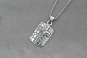 Macro shot of vintage cross pendant necklace with textured organic details and box chain