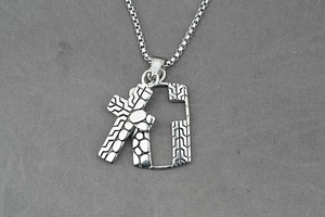 Macro shot of silver cross pendant with geometric texture on gray fabric background