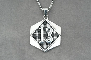 Close-up of a silver hexagonal pendant featuring a number 13 relief on a box chain