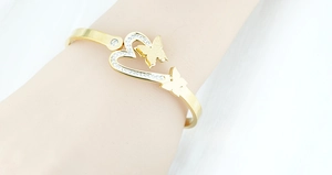 Detail of gold butterfly and heart bangle with cubic zirconia inlay on model wrist