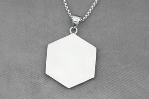 Macro detail of polished hexagonal stainless steel pendant on a round link chain