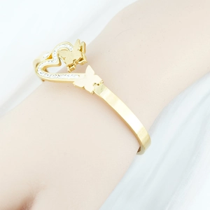 Gold butterfly cuff bracelet with heart-shaped diamond-set frame on a white fabric
