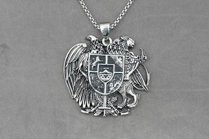 Macro view of vintage eagle and lion shield pendant on a stainless steel square link chain
