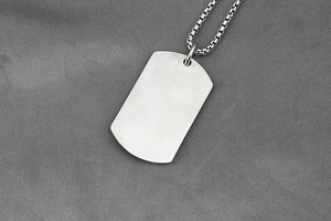 Macro detail of a brushed silver stainless steel military dog tag pendant with box chain