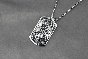 Macro view of retro skull with wings dog tag pendant on a steel box chain necklace
