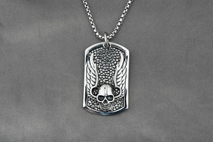 Detailed close-up of a vintage skull pendant with wings on a steel box chain