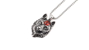 Détail d'un pendentif tête de loup vintage avec oeil rouge sur une chaîne en acier