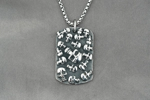 Détail d'un collier gothique en acier avec motifs tête de mort gaufrés sur pendentif rectangulaire