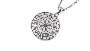 Macro shot of silver Viking Vegvisir compass pendant with Nordic runes on stainless steel