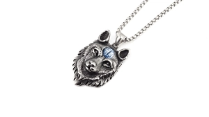 Détail du pendentif tête de loup vintage avec perle bleue et chaîne en acier