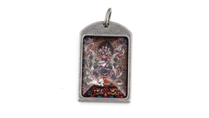 Macro view of vintage titanium steel Mahakala pendant with detailed colorful deity icon