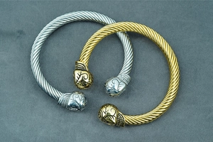 Detail of gold and silver twisted cable cuffs with decorative engraved end caps