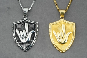 Detalle de los colgantes de escudo con gestos de manos en relieve en acero dorado y plata