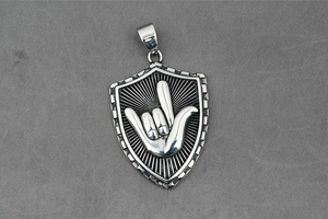 Detalle del colgante de escudo vintage con relieve de gesto de mano y patrón radial