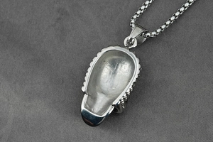 Macro shot of silver punk skull pendant back detail with textured edge on box chain