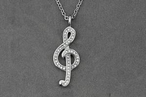 Detailed macro view of a silver treble clef pendant encrusted with sparkling crystals