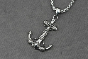 Detailed macro view of silver anchor pendant with rope texture on box chain necklace