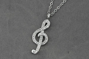 Detailed view of silver treble clef pendant with shimmering white cubic zirconia stones