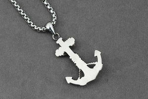 Detailed view of silver stainless steel anchor cross pendant on a thick box chain link